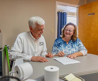 Two people talking and completing paperwork