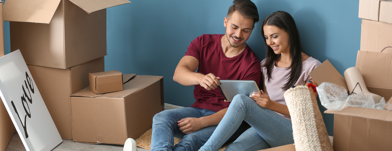 a couple sitting amid boxes in their new home