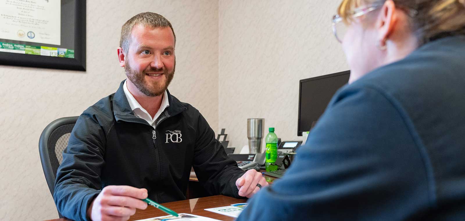 man smiling while sitting at his desk helping a customer