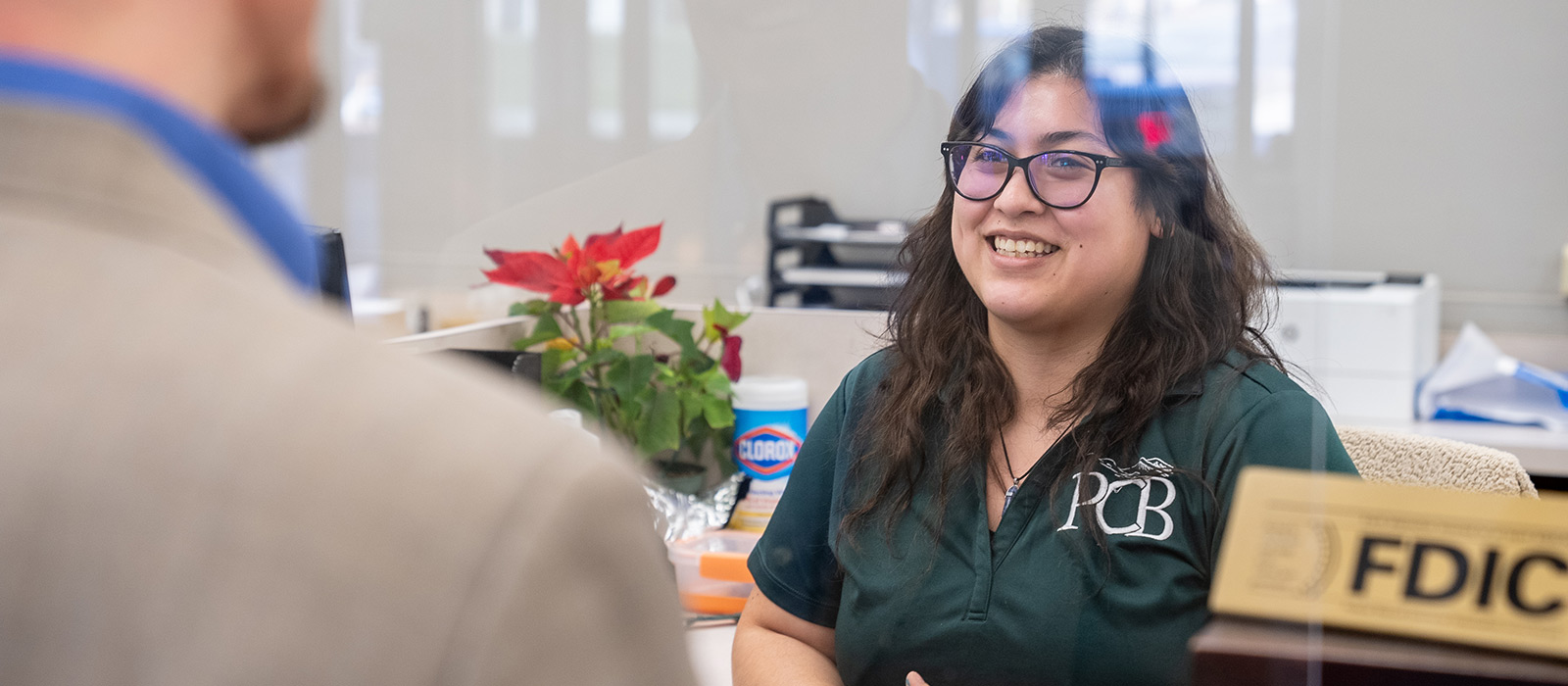 woman smiling behind teller line talking to a customer