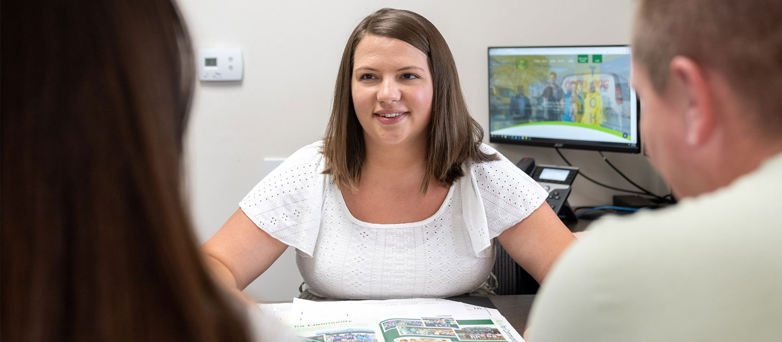 Woman team member smiling and looking at 2 customers