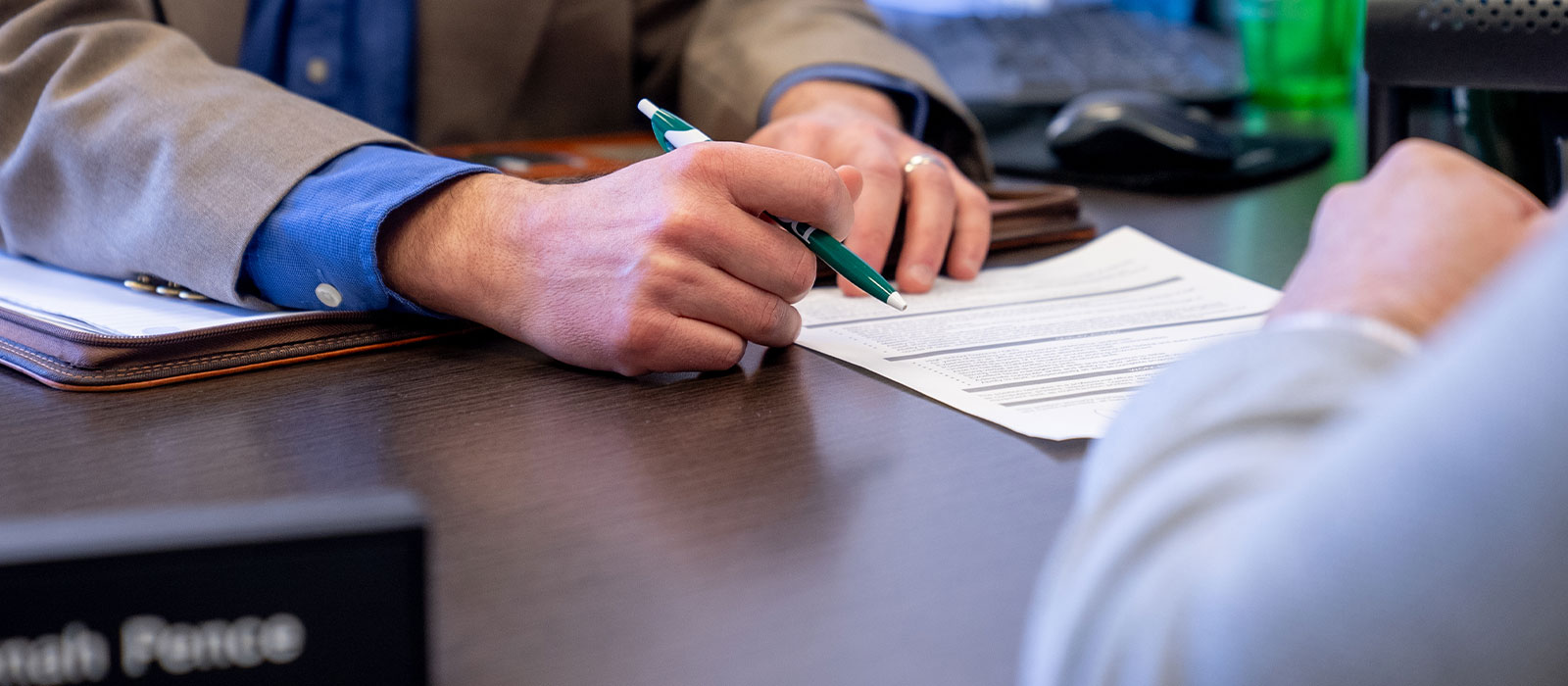 hands of two men looking at a paper on a desk